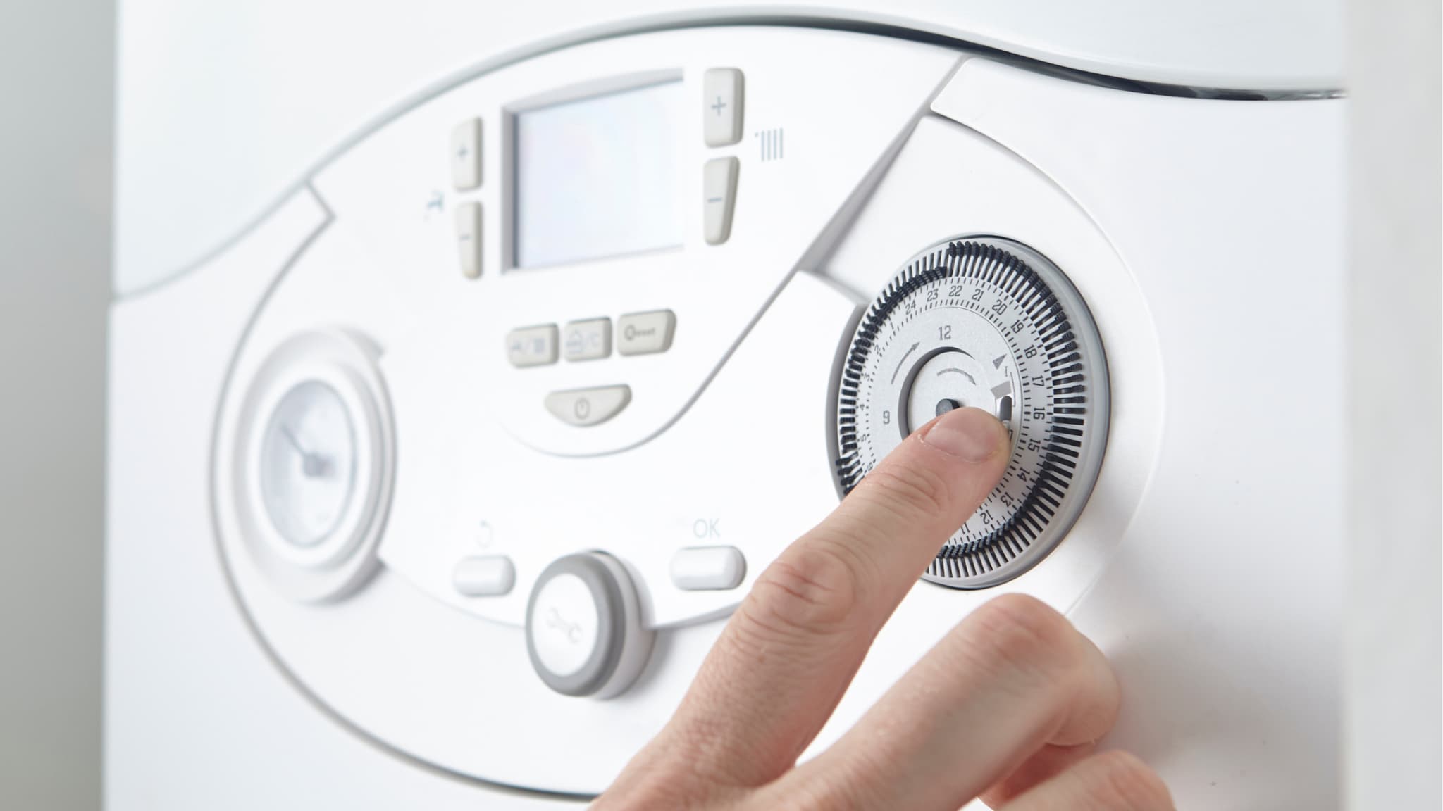 A finger pressing the timer dial on a boiler control panel